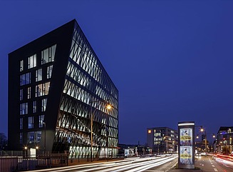 Kontorbygning med mørk facade og skrånende højre side af facaden