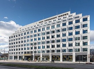11-geschossiges weißes Gebäude mot Ladenflächen im Erdgeschoss und dem Schriftzug The Student Hotel