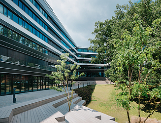 L-förmiges Bürogebäude mit horizontal durch weiße Fensterelemente strukturierte Fassade