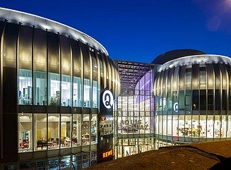 To runde glasbygninger, forbundet af en passage, med Aquis Plaza i rødt over indgangen