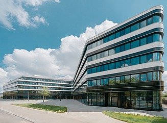 L-förmiges Bürogebäude mit horizontal durch weiße Fensterelemente strukturierte Fassade