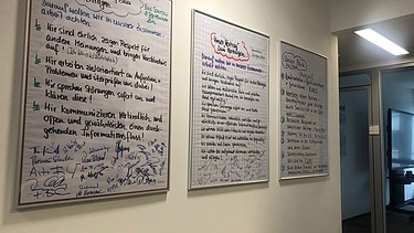 three framed agreements on cooperation written in felt-tip pen on the wall of an office corridor