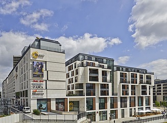 Hvide boligblokke med delvist fremspringende kasseformede vinduesoverliggere, sort overbygning på øverste etage