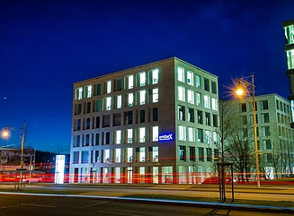 Bright corner building with many windows, in front of it a stele with the number 23