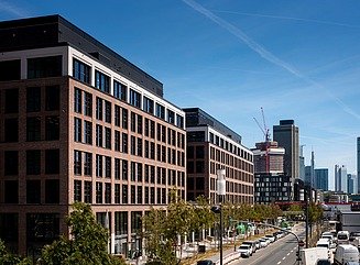 Two office blocks with brick-look clinker facades on a street with trees