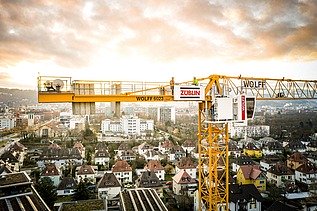 Gelber Kran mit Logos von Züblin und Wolff vor einem Stadtpanorama