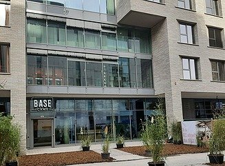 Residential building with façade of light-colored stone and glass, Base Camp lettering above the entrance