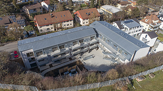 Nachtansicht eines im Wald gelegenen L-förmigen Gebäudekomplexes