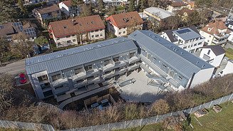 Nachtansicht eines im Wald gelegenen L-förmigen Gebäudekomplexes