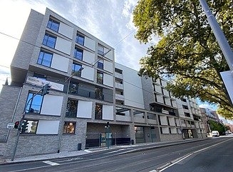 Boligbygning med grå klinker og hvide dekorative elementer ved siden af vinduerne