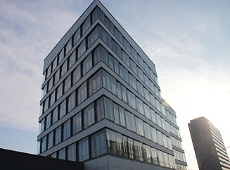 White building with shop windows on the ground floor, ADAC lettering on the white surface, 5 storeys above, yellow ADAC logo on the building