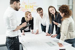 Group of people standing around a table and discussing a construction plan