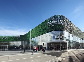 Geschwungene begrünte Fassade eines Verkaufsgebäudes, Schriftzug Saturn über dem Eingang