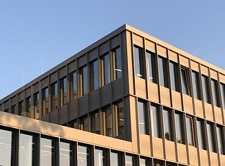 Bürogebäude mit strukturierter Fassade, hohen schmalen Fenstern und Eingangsbereich mit Säulen