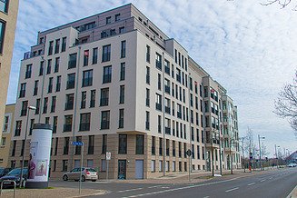 Billedet viser nybyggeriet af et boligkompleks med en beige facade.