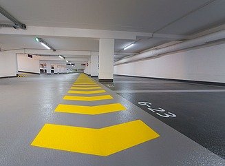 Parkhaus von innen, im Vordergrund gelbe Markierungen, hinten Säulen und Blick nach drißen