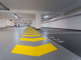 Parkeringspladsen set indefra, gule markeringer i forgrunden, søjler og udsigt bagud