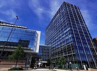 T-förmig angeordnete Glasfassaden eines Bürogebäudes, unter dem eine Strasse durchführt 