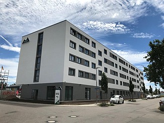 Image of a hotel with a bright façade and gray base on the corner of two streets
