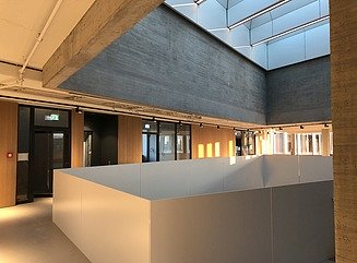 Bürogebäude mit strukturierter Fassade, hohen schmalen Fenstern und Eingangsbereich mit Säulen