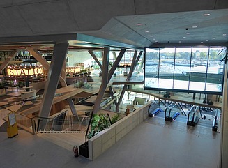Block of three buildings with glass facades on the waterfront, with three boats on top
