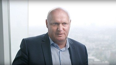 Picture of Jens Quade in conversation Jens Quade in front of a window with a city panorama in the background