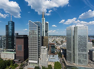 Skyline mit mehreren Hochhäusern in unterschiedlicher Höhe, davor Bäume