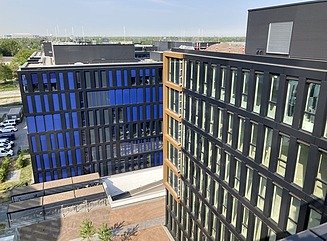 Visualisering af arkitekturen i to kontorbygninger, den ene i en firkant omkring en indre gårdhave, den anden en T-formet blok, begge med masser af glasfacader