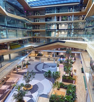 Block of three buildings with glass facades on the waterfront, with three boats on top