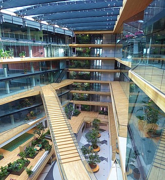 Block of three buildings with glass facades on the waterfront, with three boats on top