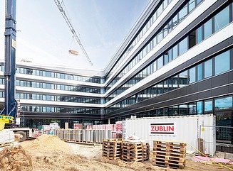 L-formet kontorbygning med en facade, der er struktureret horisontalt af hvide vindueselementer