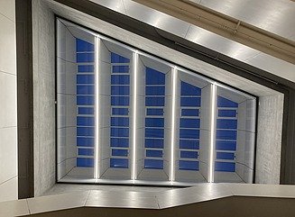 Bürogebäude mit strukturierter Fassade, hohen schmalen Fenstern und Eingangsbereich mit Säulen