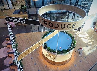 Block of three buildings with glass facades on the waterfront, with three boats on top