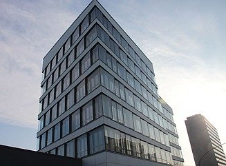 Weißes Gebäude mit Schaufenstern im Ergeschoss, Schriftzug ADAC auf der der weißen Fläche, darüber 5 Stockwerle, auf dem Bauwerk gelbes ADAC-Logo