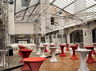 Backsteingebäude mit zwei Rundbogeneingängen, unten Fenster mit Zackenverzierung aus Backstein, darüber viele Fenster mit weißen Rahmen