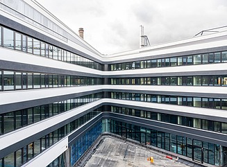 L-formet kontorbygning med en facade, der er struktureret horisontalt af hvide vindueselementer